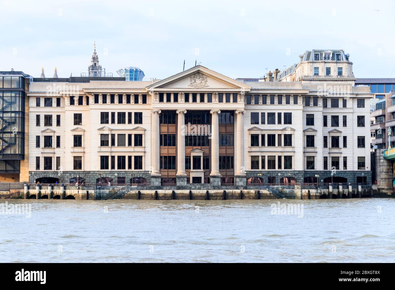 The classical granite and limestone riverside facade of Vintners Place in  Upper Thames Street, from across the River Thames, Southwark, London, UK Stock Photo