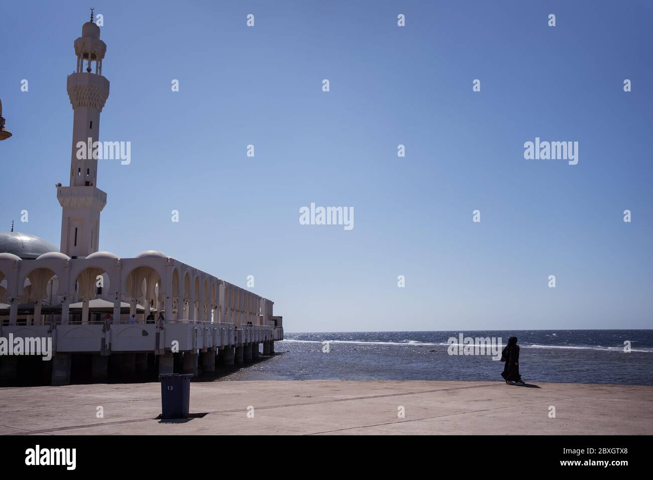 Jeddah / Saudi Arabia - January 20, 2020: Muslim woman with black abaya near beautiful Mosque near the sea Stock Photo