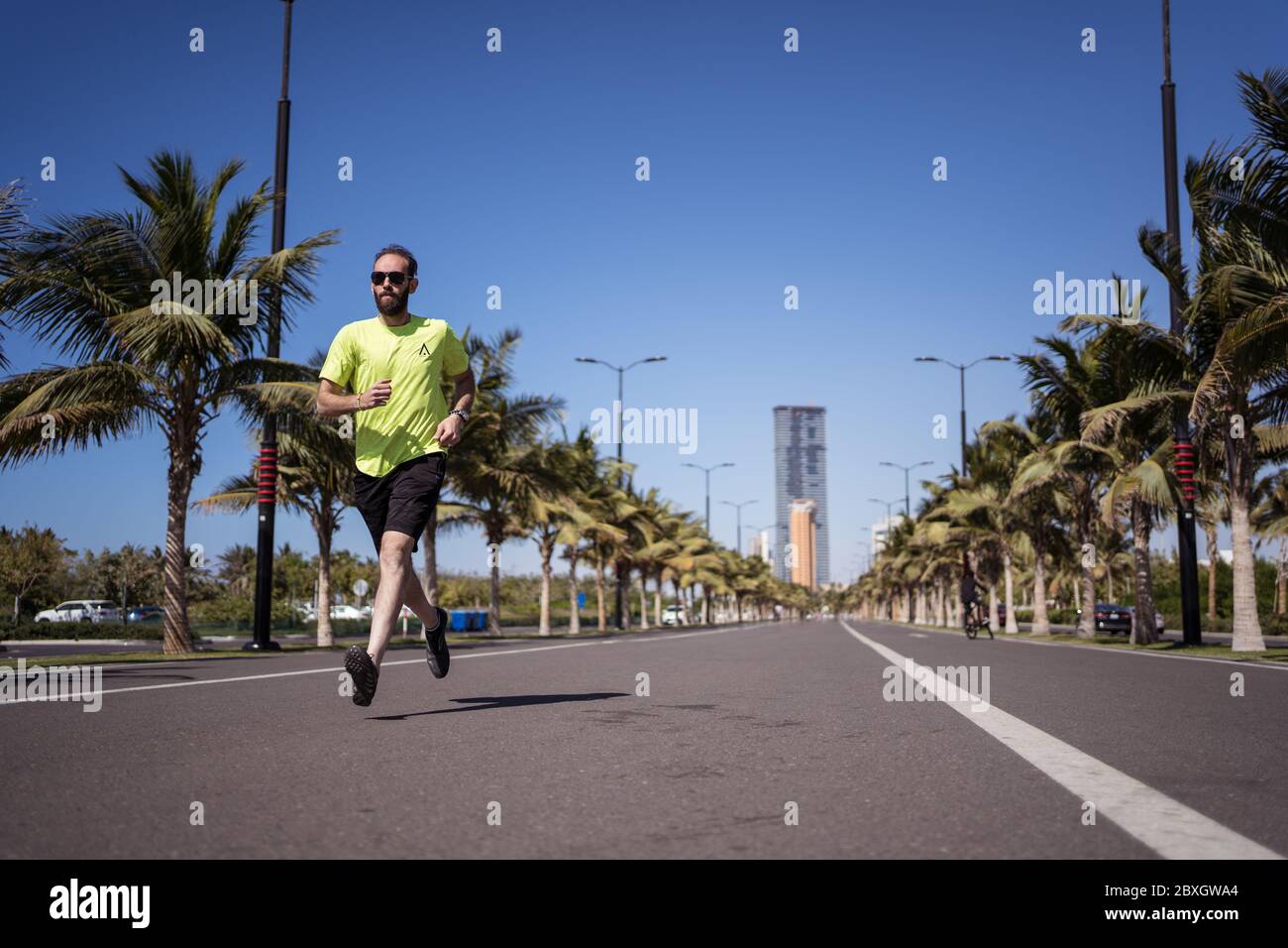 Jeddah / Saudi Arabia - January 20, 2020: Man running in sport clothes in avenue without cars Stock Photo