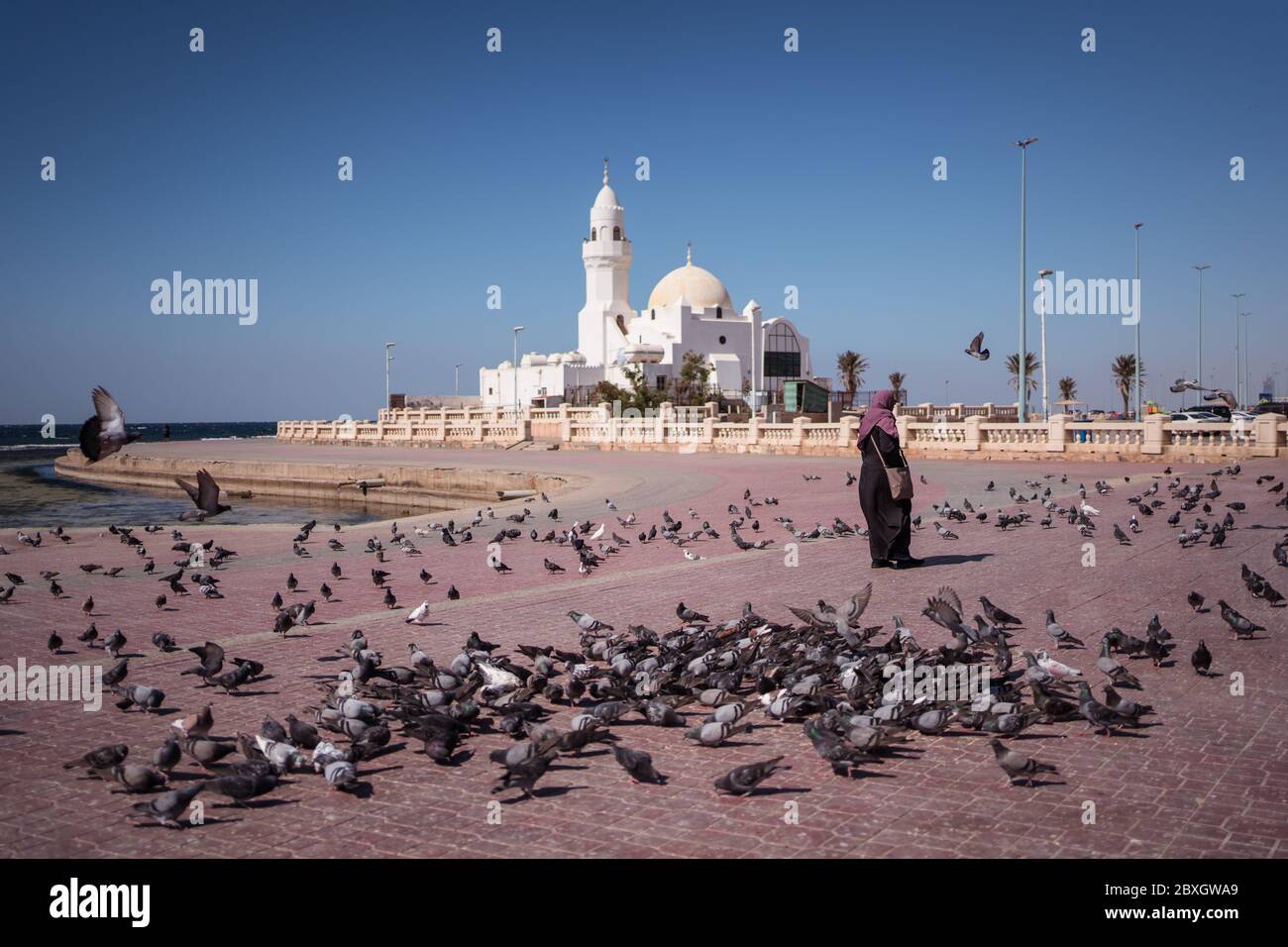 Jeddah / Saudi Arabia - January 20, 2020: Muslim believers feeding pigeons near beautiful Mosque near the sea Stock Photo