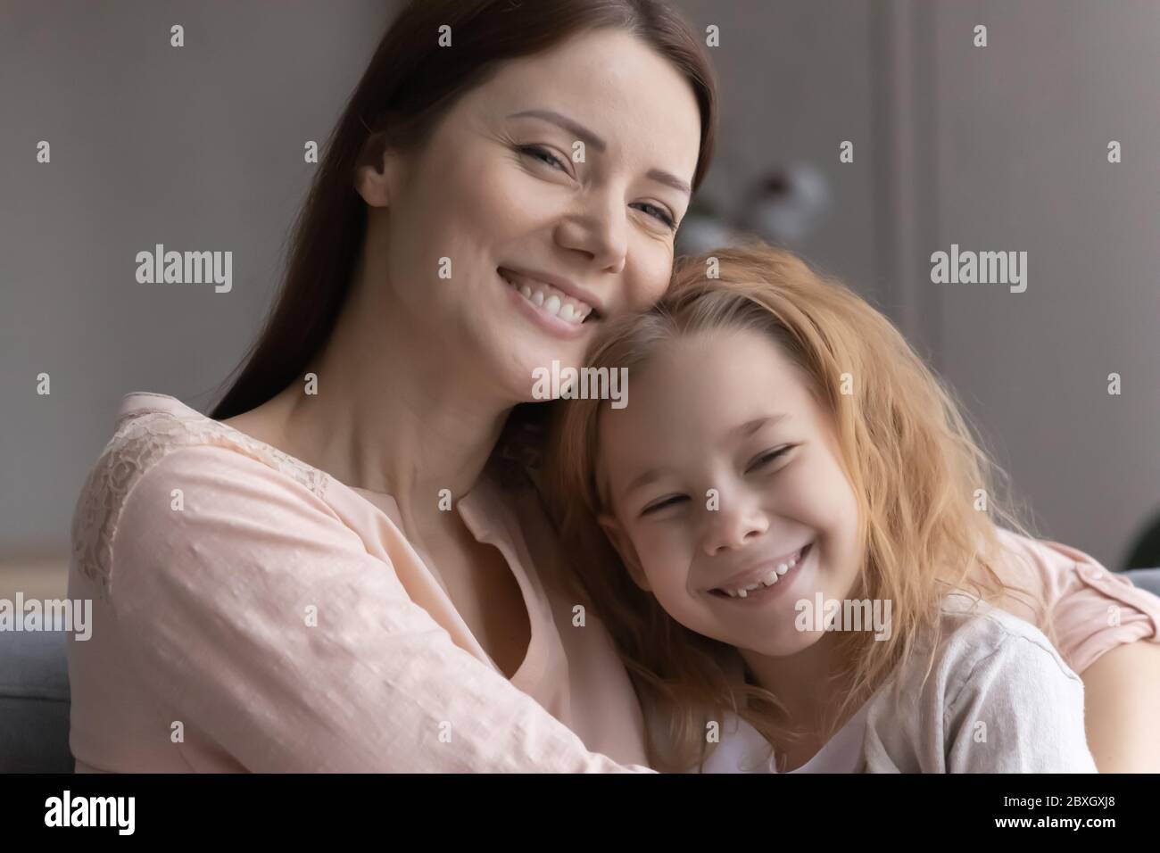 Portrait of smiling young mom and little daughter hugging Stock Photo