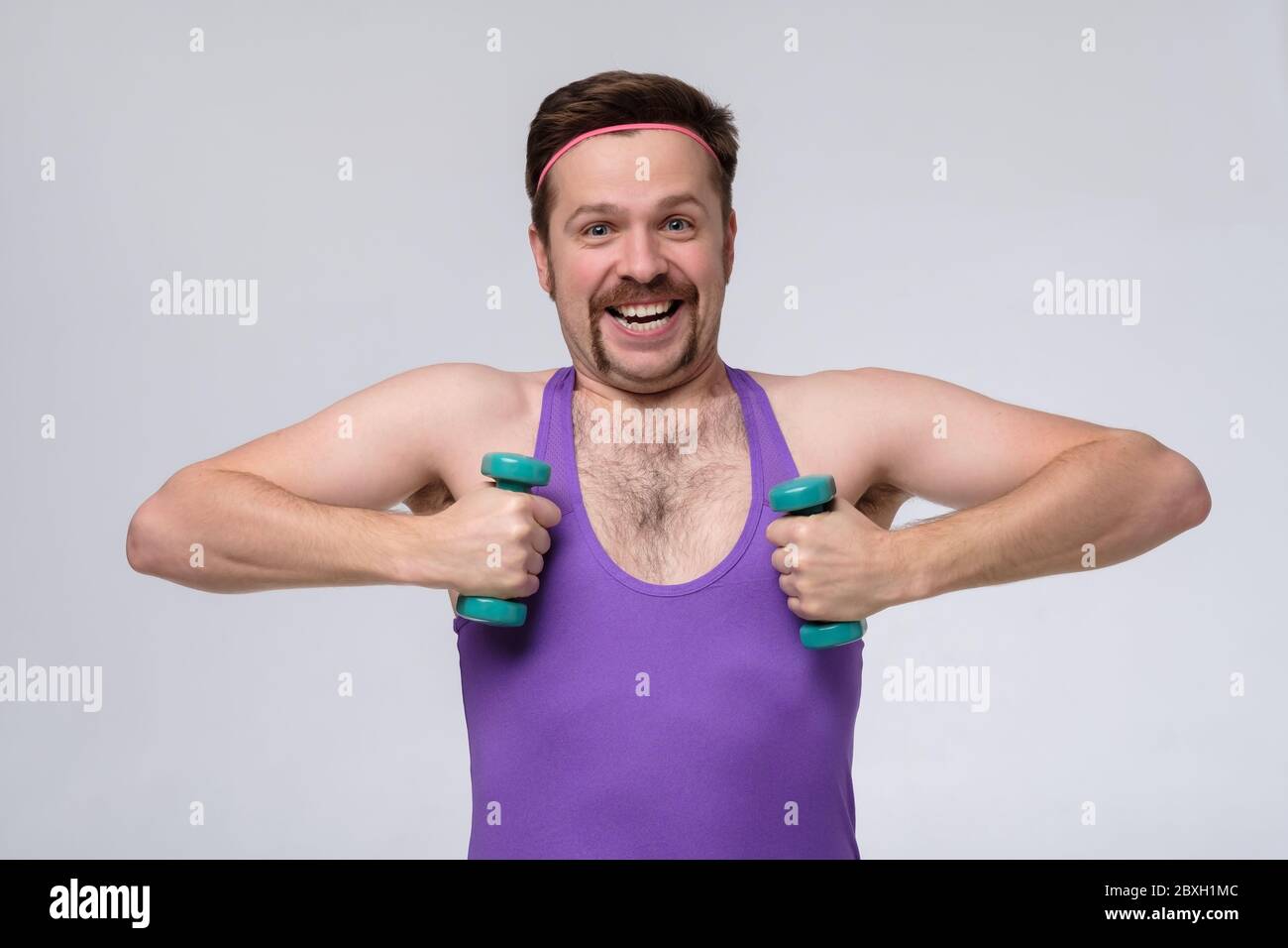 Athletic funny young man doing exercise dumbbell. Studio shot Stock Photo