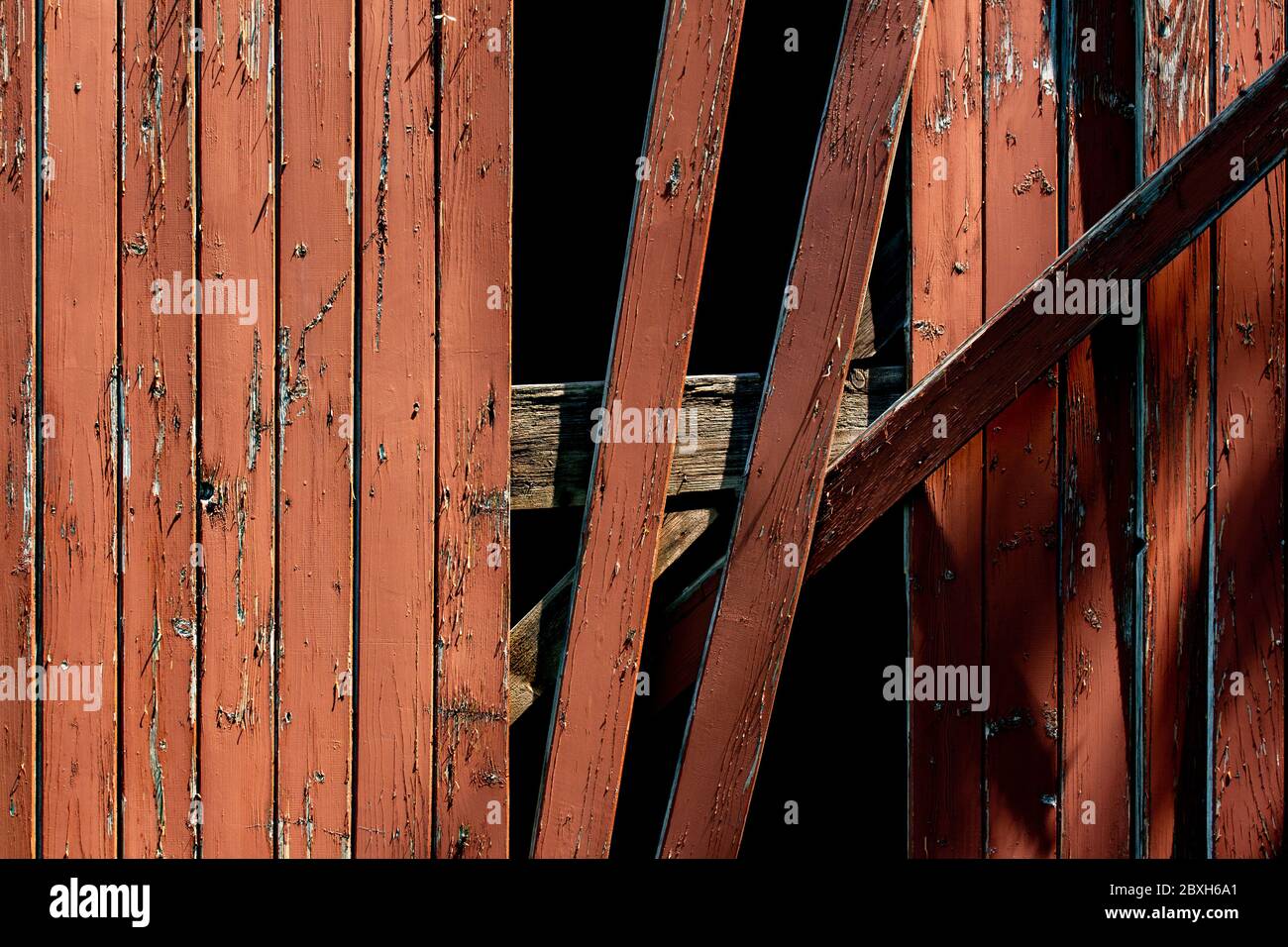 Red wooden plank wall with damaged planks hanging down Stock Photo