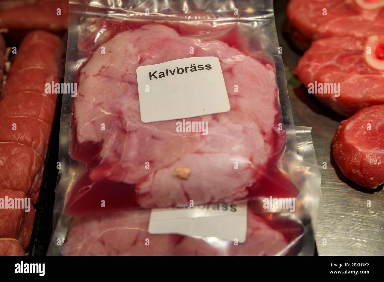 Packages raw veal sweetbreads next to other meat cuts on display at a food market butcher stall in Stockholm, Sweden, label saying sweetbreads Stock Photo