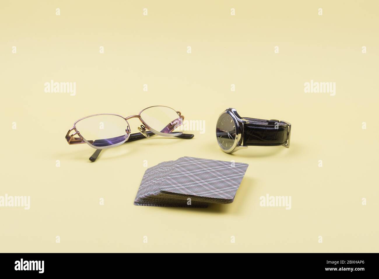 Glasses, wrist watches with a leather strap and a deck of cards. Yellow