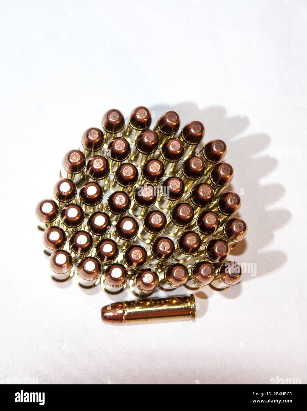 several 22 mm long rifle bullets standing on end on a white background.  One lying down. Stock Photo