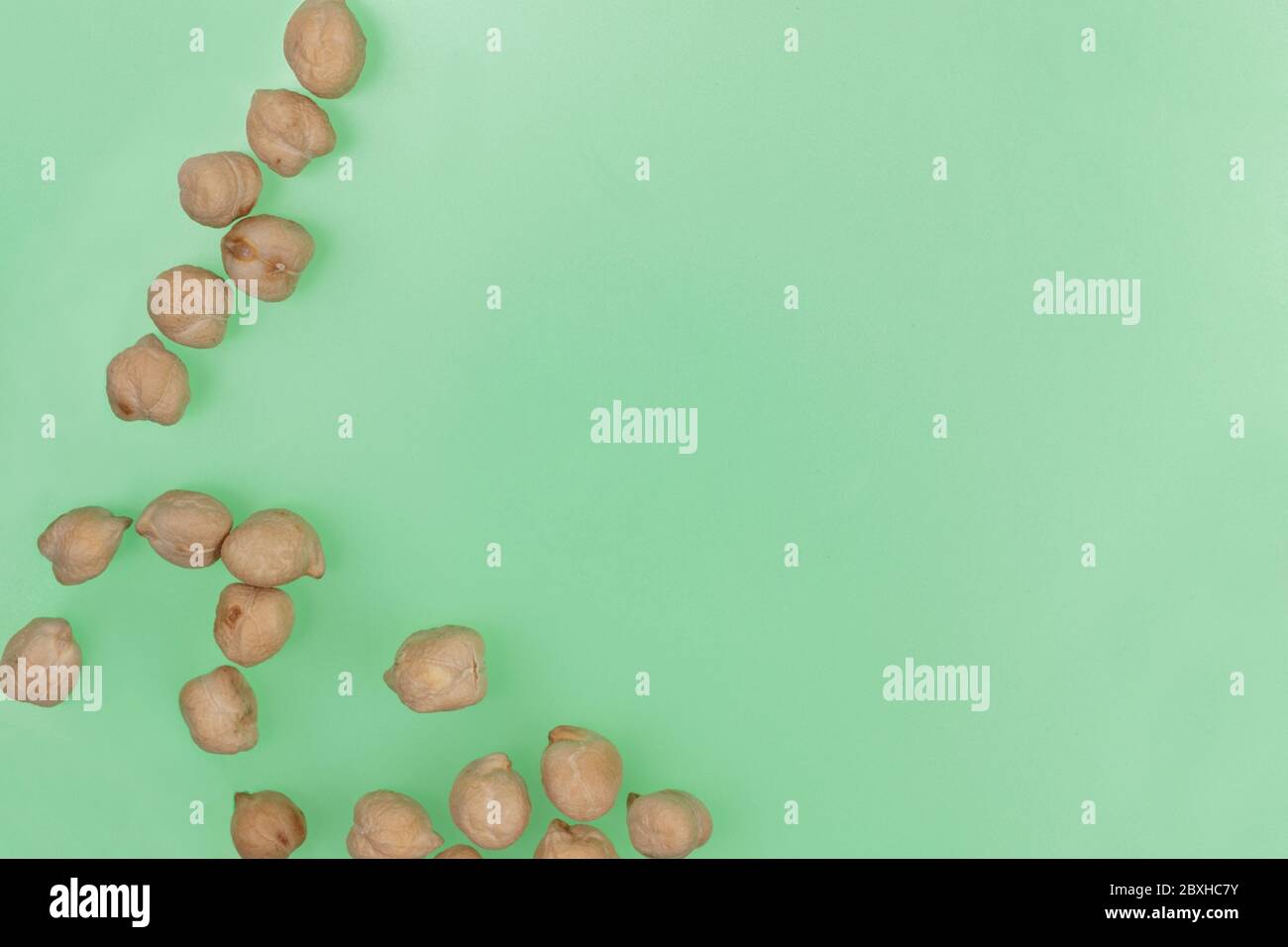 scattered, dry garbanzo beans or chick peas on a green background with copy space Stock Photo