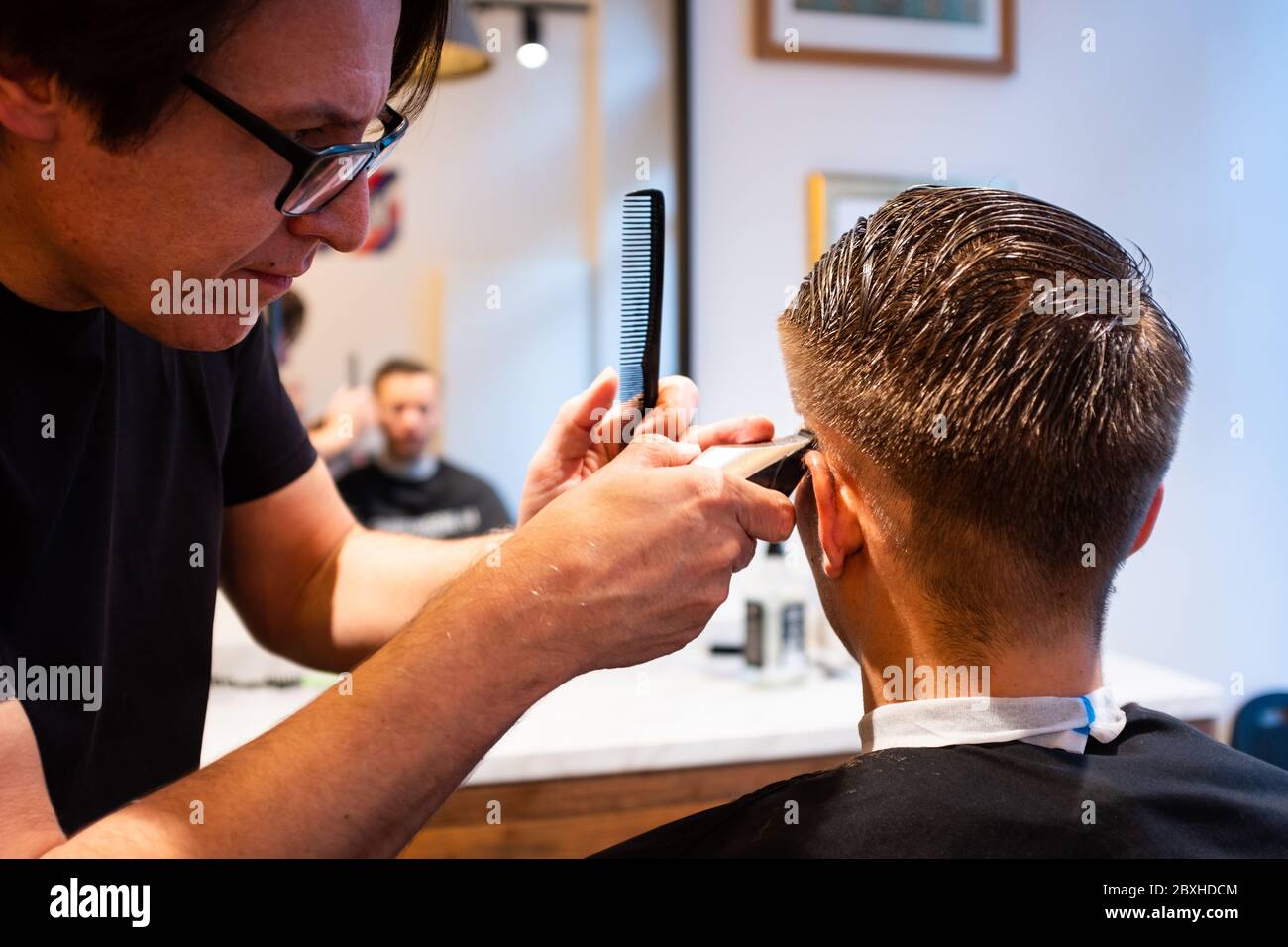 Barber Sample Using Razor Barber trims the hair of a young man with a razor in his barbershop ...