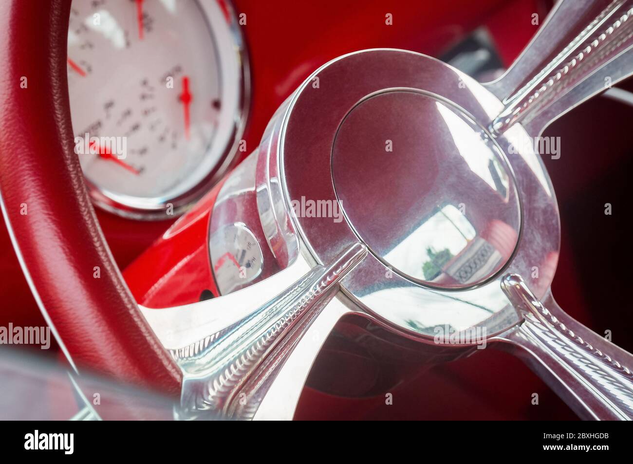 Steering wheel with crome beams, fuel, oil, water, volts dials on front panel of red old timer car Stock Photo