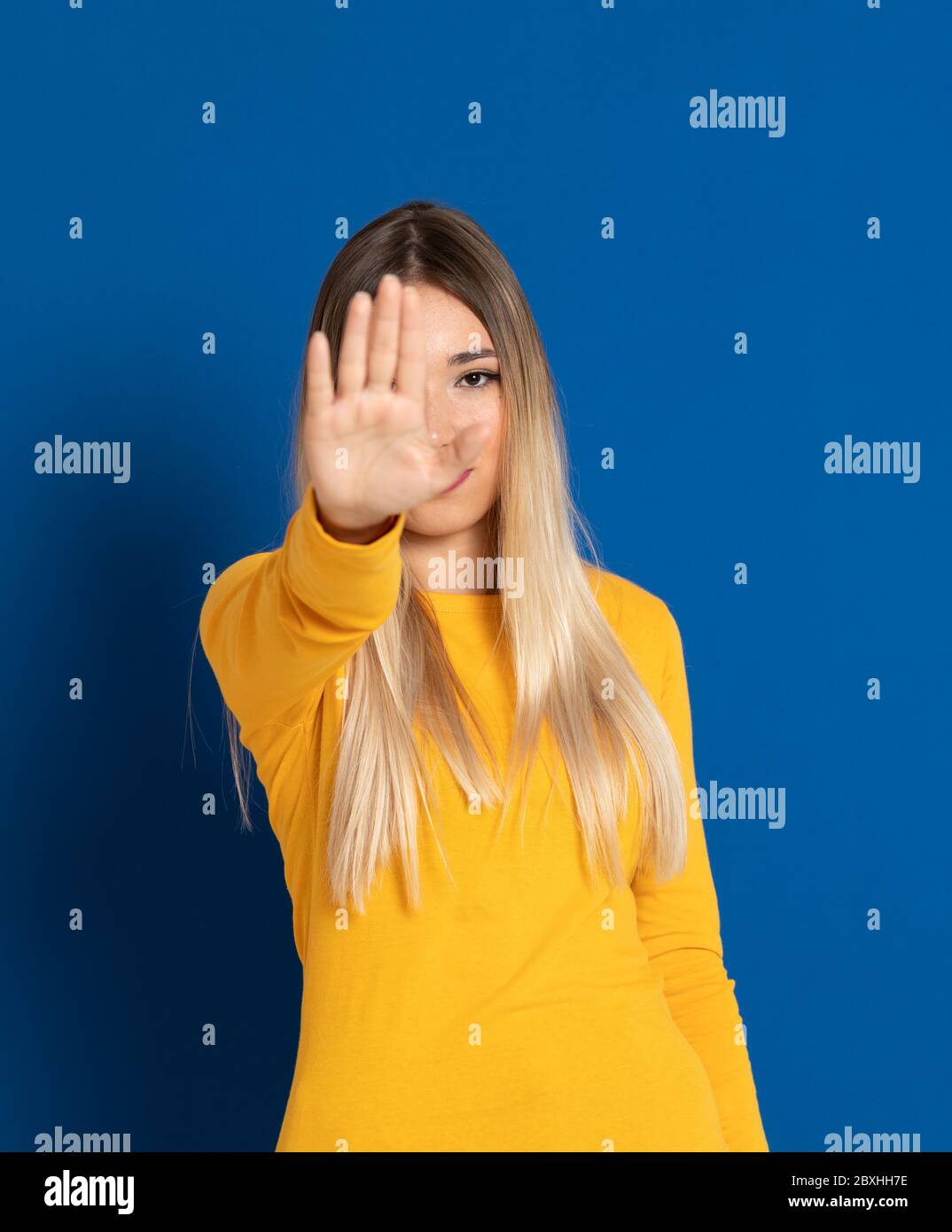 Blonde girl wearing a yellow T-shirt on a blue background Stock Photo