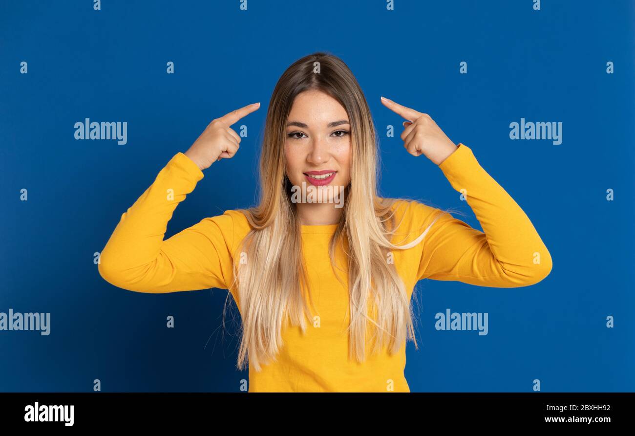 Blonde girl wearing a yellow T-shirt on a blue background Stock Photo