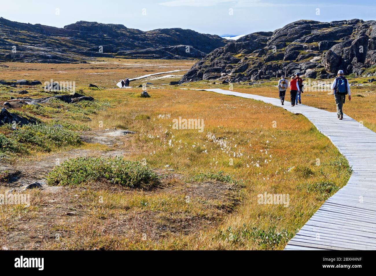 Tourists hike along boardwalk across tundra leading to Jakobshavn (also known as Sermeq Kujalleq) Glacier overlook at Ilulissat, Greenland. Stock Photo
