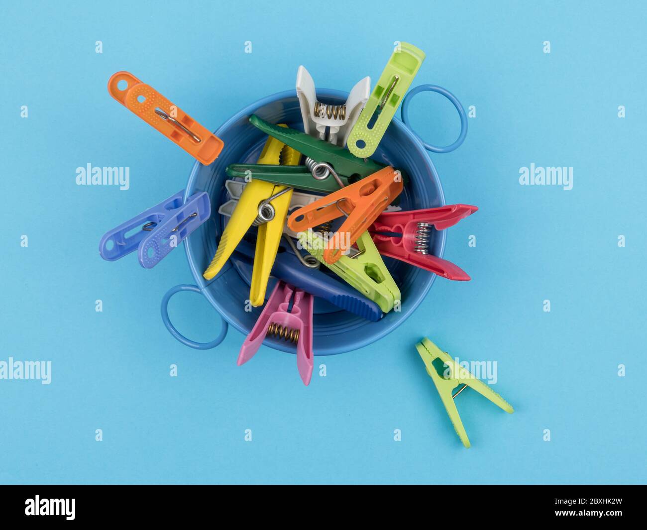 Colored clothespins in the container on the blue background Stock Photo ...