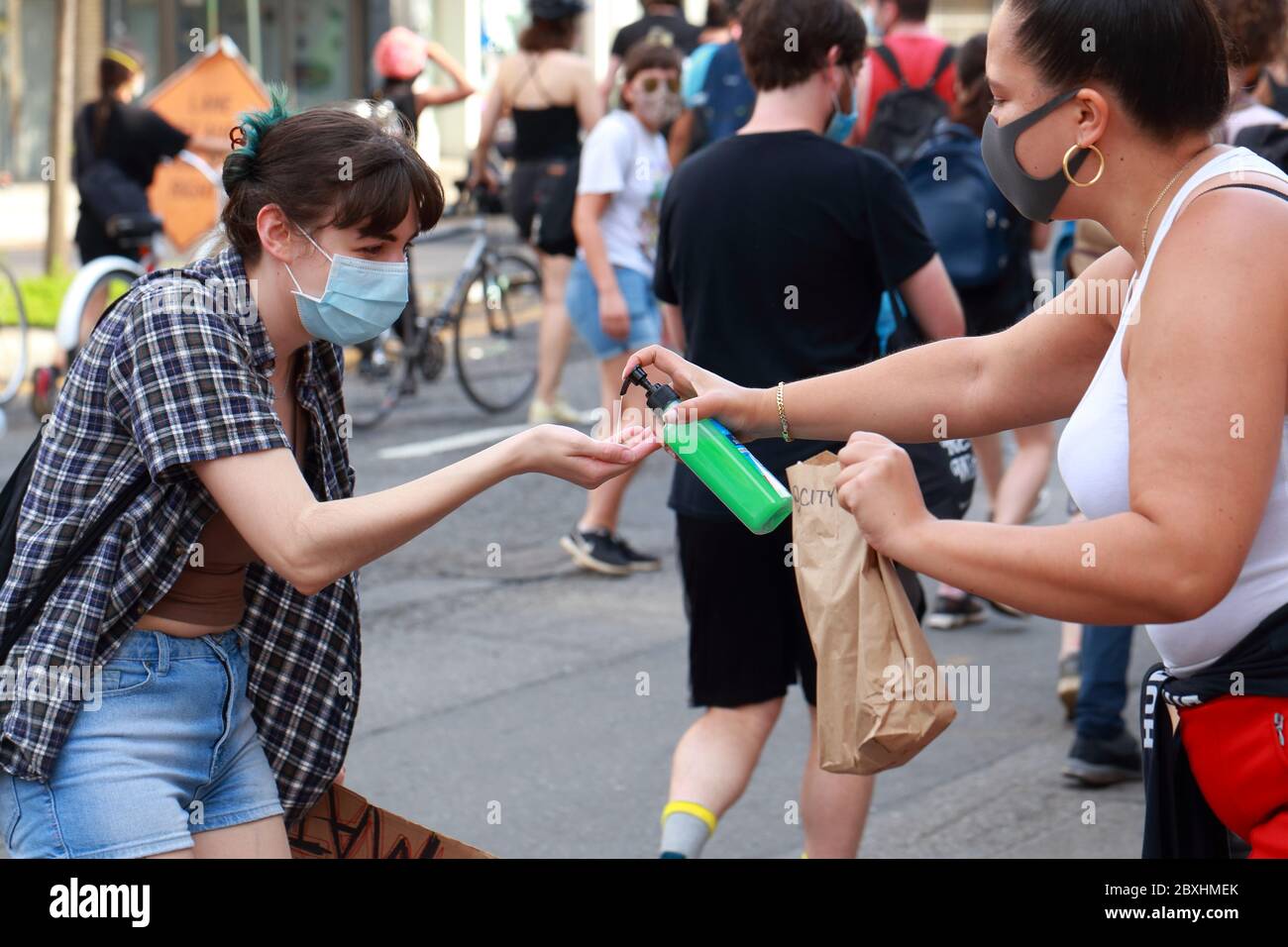 New York, NY. 6th June 2020. A person with a mask dispenses hand sanitizer and snacks at a Black Lives Matter solidarity march through Manhattan calling for justice in a recent string of American police killings: George Floyd, Breonna Taylor, and to countless others. Some people and groups have quickly setup water, snack, and hand sanitizing stations anticipating the arrival of marchers through their area. June 6, 2020 Stock Photo