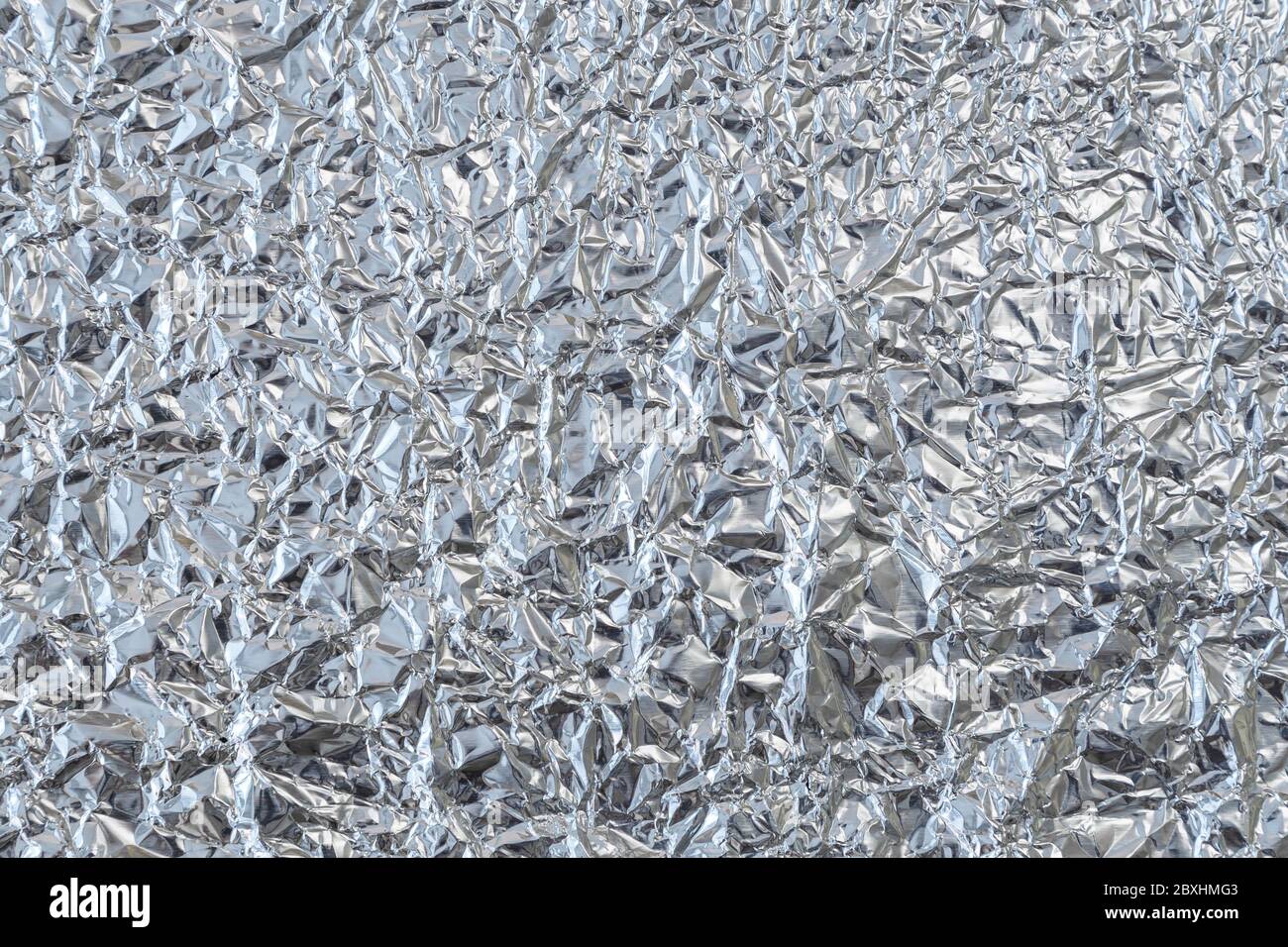 Close-up of crumpled tin foil surface, top view. Abstract full frame textured silvery background. Stock Photo