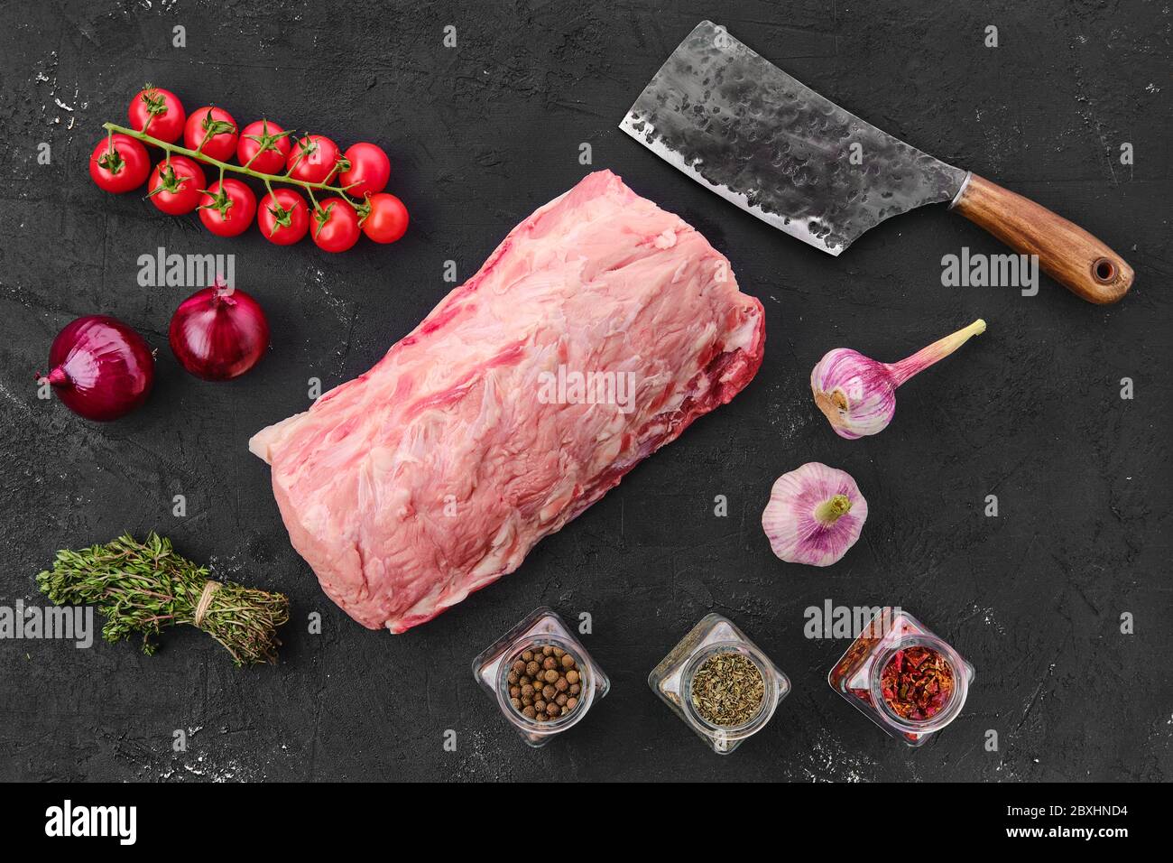 Raw fresh pork collar joint meat on black background with spice, top