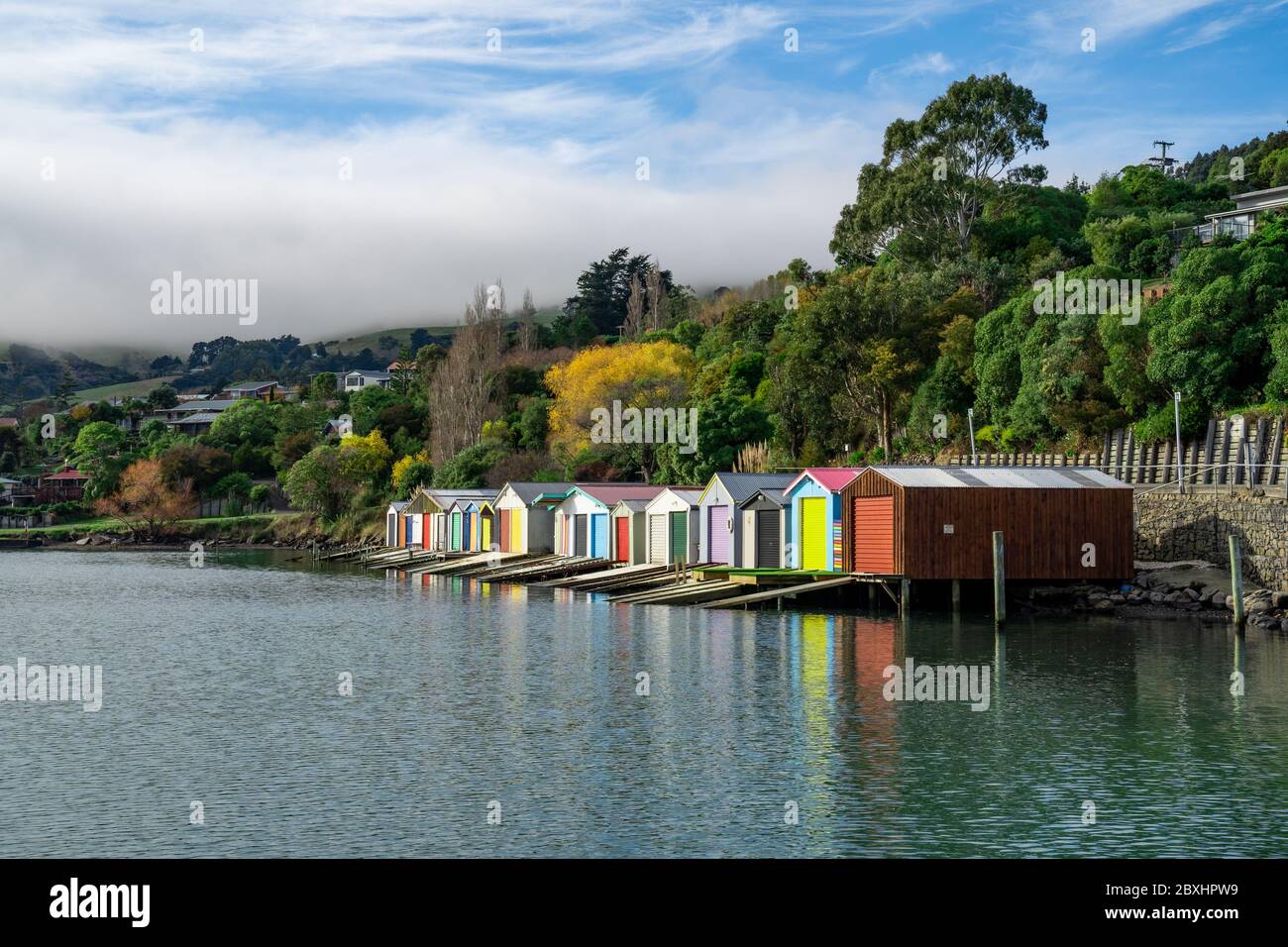 Colorful Boat Sheds with beautiful reflection on daytime  at Duvauchelle, Akaroa Harbour on Banks Peninsula in South Island, New Zealand. Stock Photo
