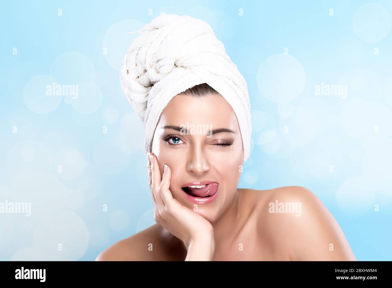 Beautiful girl after shower winking with towel on head and funny
