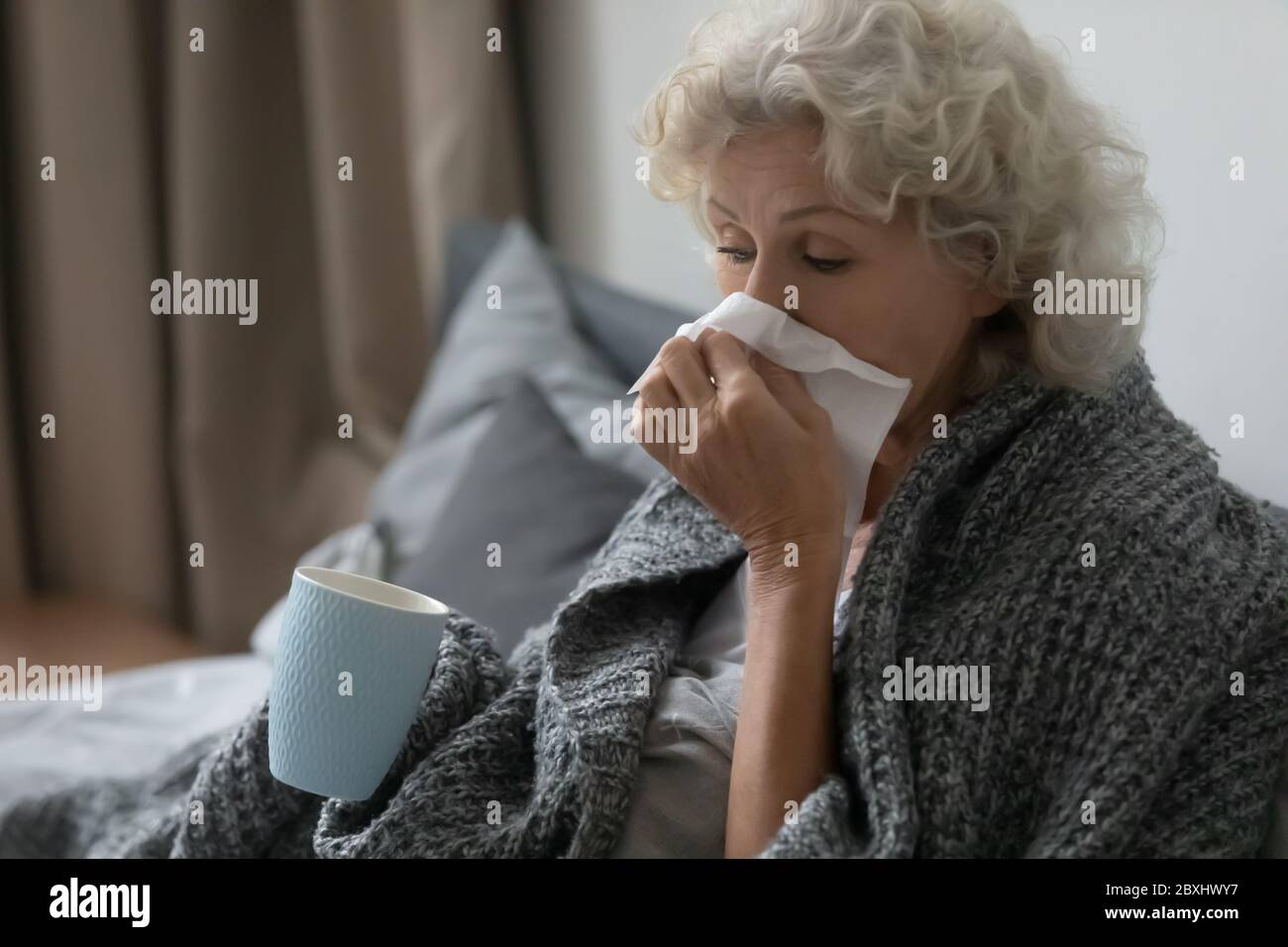 Unwell senor woman suffer from flu in home bed Stock Photo