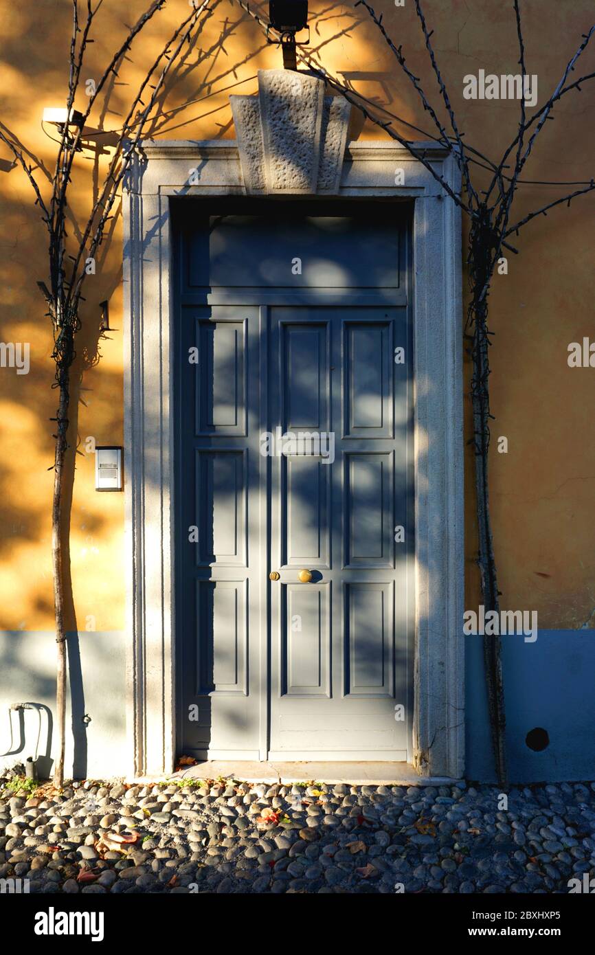 Sunny blue door entrance to a cosy yellow-orange house in Bergamo, Italy. Stock Photo