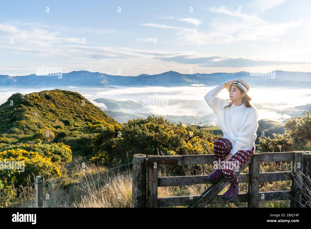 Happy carefree asian woman enjoying nature with layers of mountains and the mist in the morning at The peak of Bank Peninsula, Akaroa, New Zealand. Stock Photo
