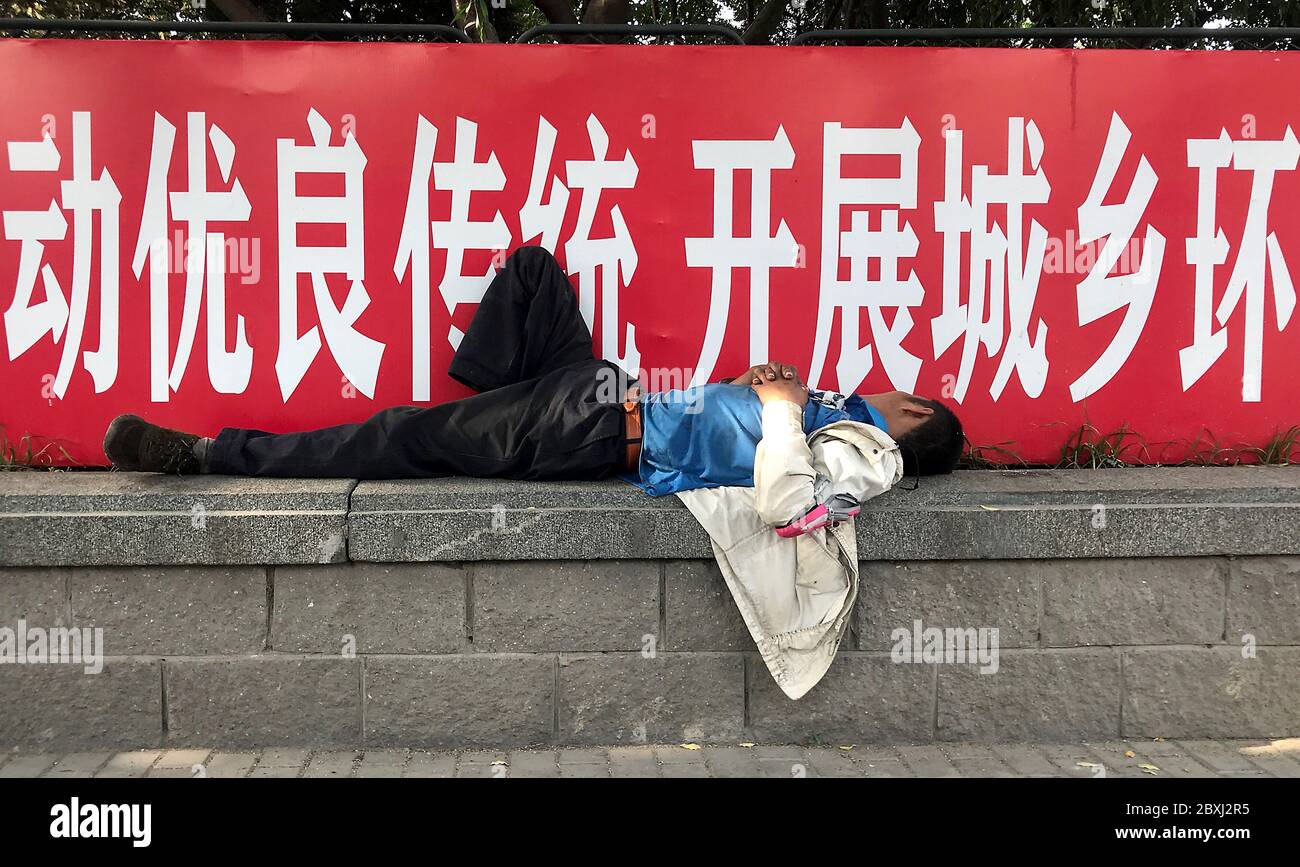 Beijing, China. 07th June, 2020. A Chinese migrant worker naps in the shade next to a banner promoting safety and being a good citizen in Beijing on Sunday, June 7, 2020. High unemployment in both the country and big cities due to the Covid-19 outbreak remains an obstacle to complete economic recovery and a threat to social stability. Photo by Stephen Shaver/UPI Credit: UPI/Alamy Live News Stock Photo