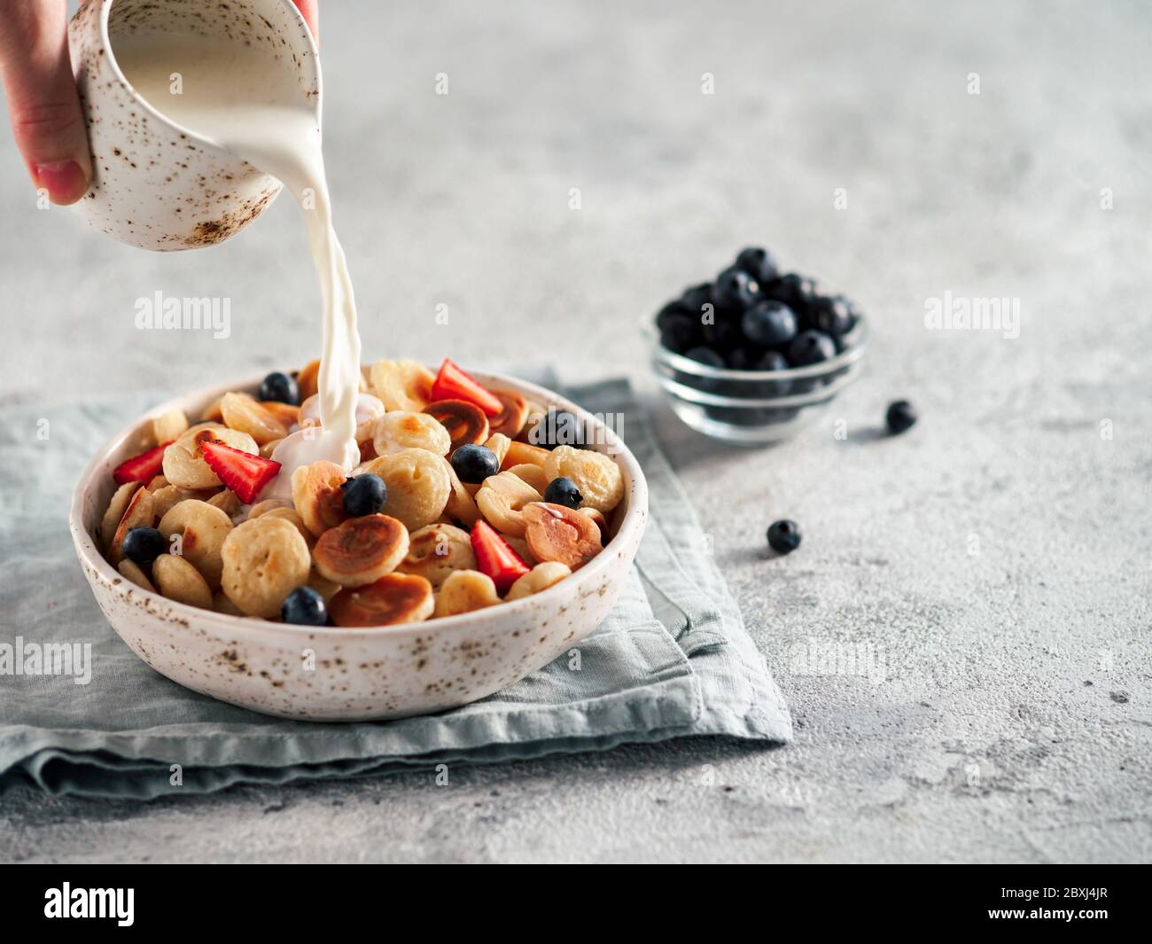 Trendy food pancake cereal. Milk pouring on heap of mini cereal