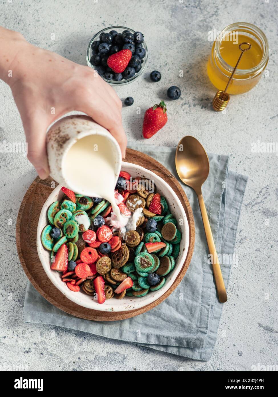 Trendy food pancake cereal. Milk pouring on heap of multicolor mini