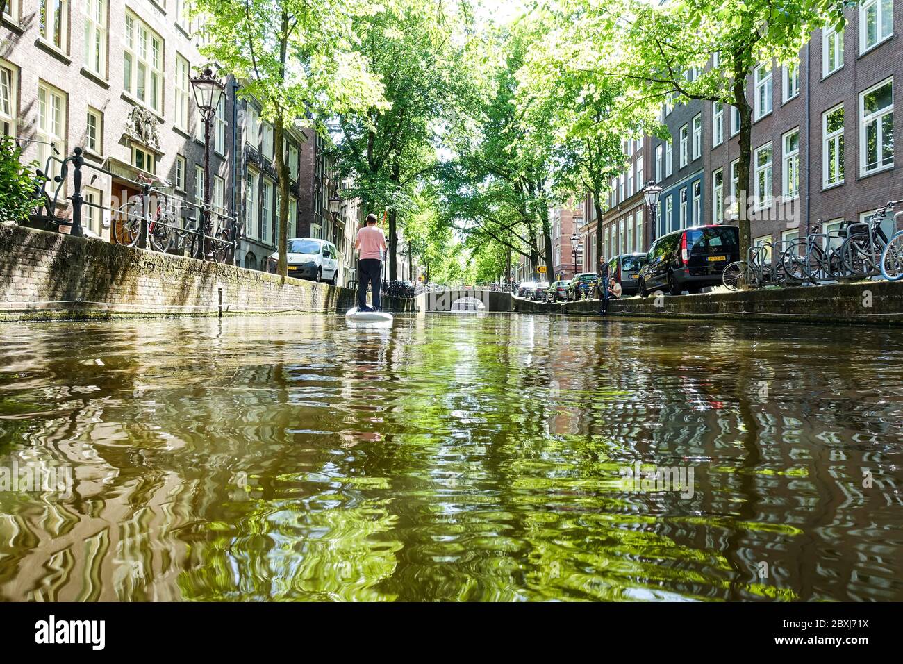 Man on a SUP (stand-up paddle board) on the canals in the center of quiet Amsterdam (Netherlands) during the Covid-19 crisis Stock Photo
