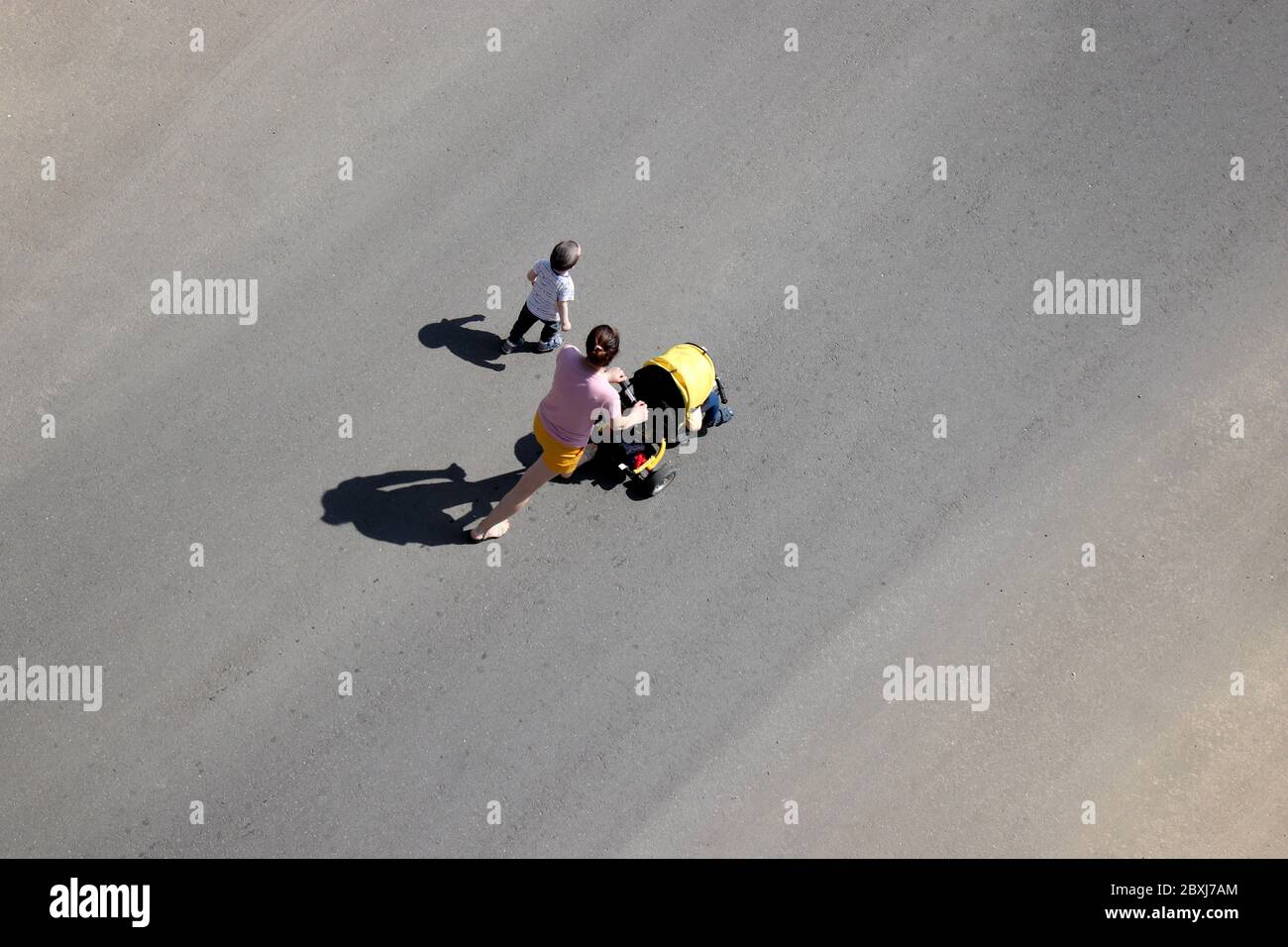 Woman with two kids crossing the street, top view. Concept of motherhood, road safety, single mom with children Stock Photo
