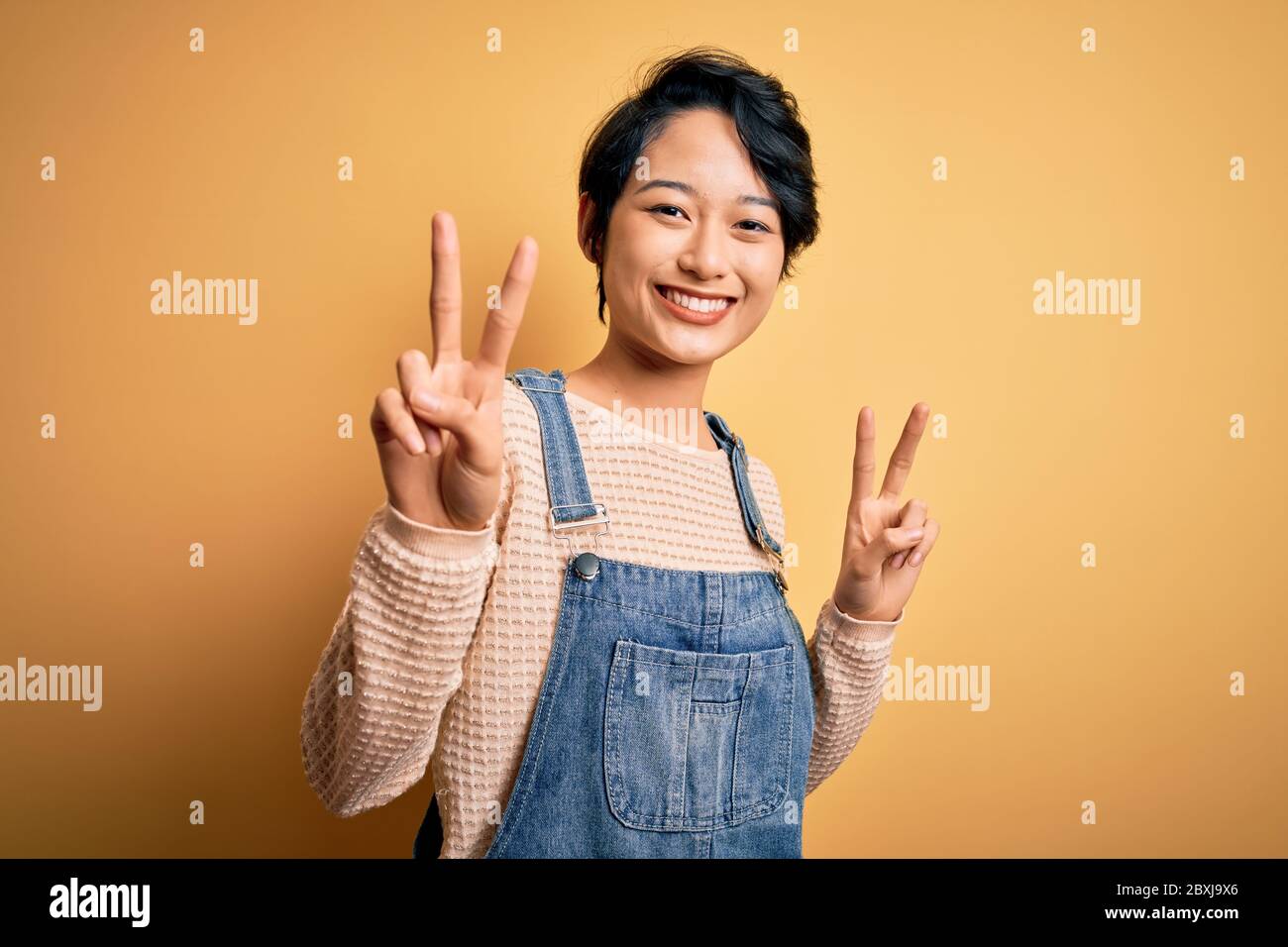Young beautiful asian girl wearing casual denim overalls over isolated ...