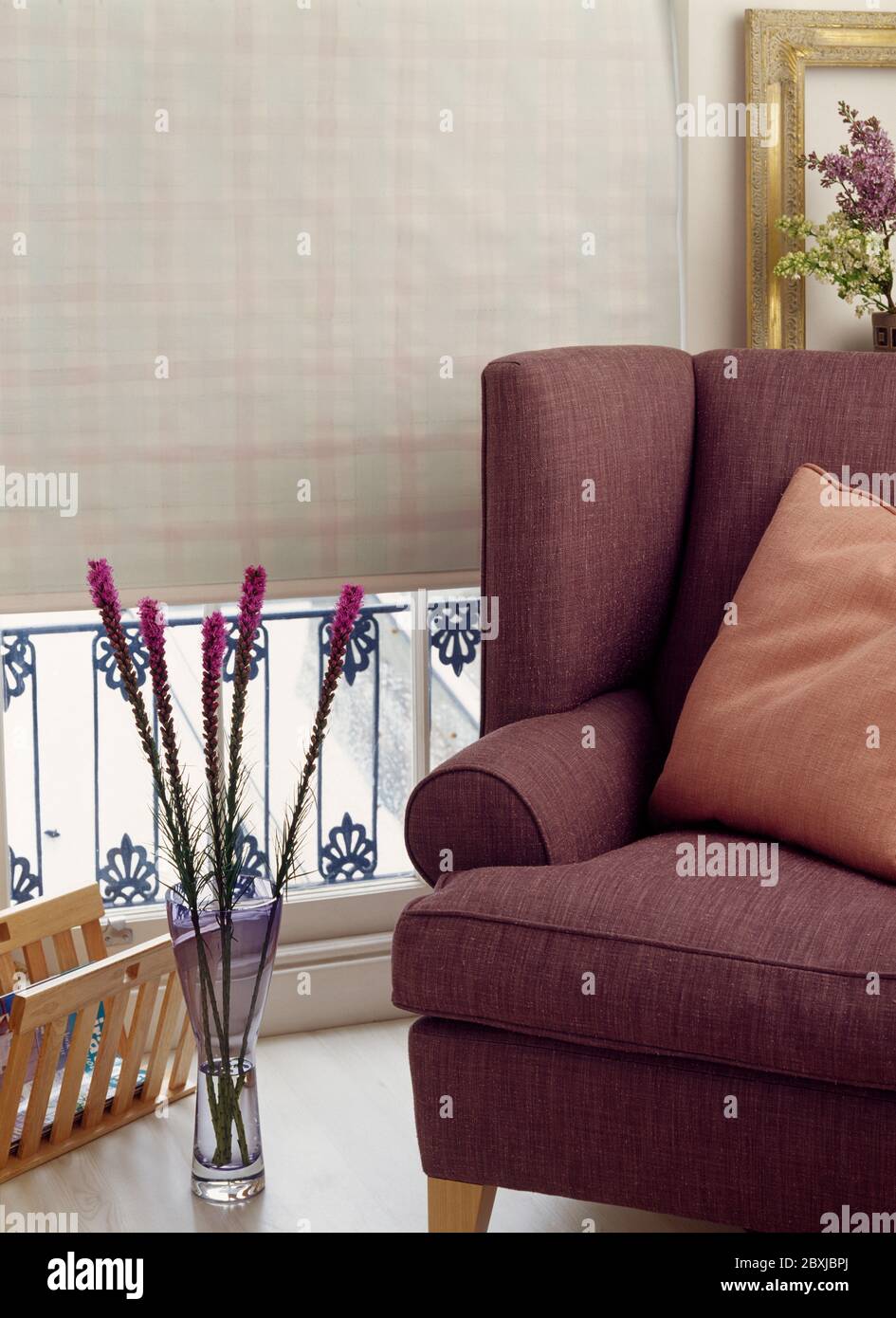 Closeup of brown covered easy chair in front of chequered roller blind Stock Photo