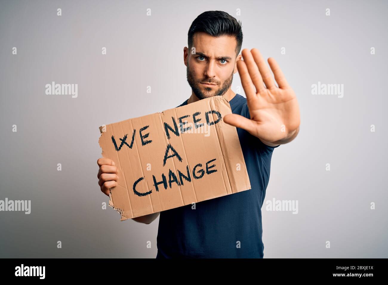 Young handsome activist man protesting for the enviroment hoding cardboard with open hand doing stop sign with serious and confident expression, defen Stock Photo