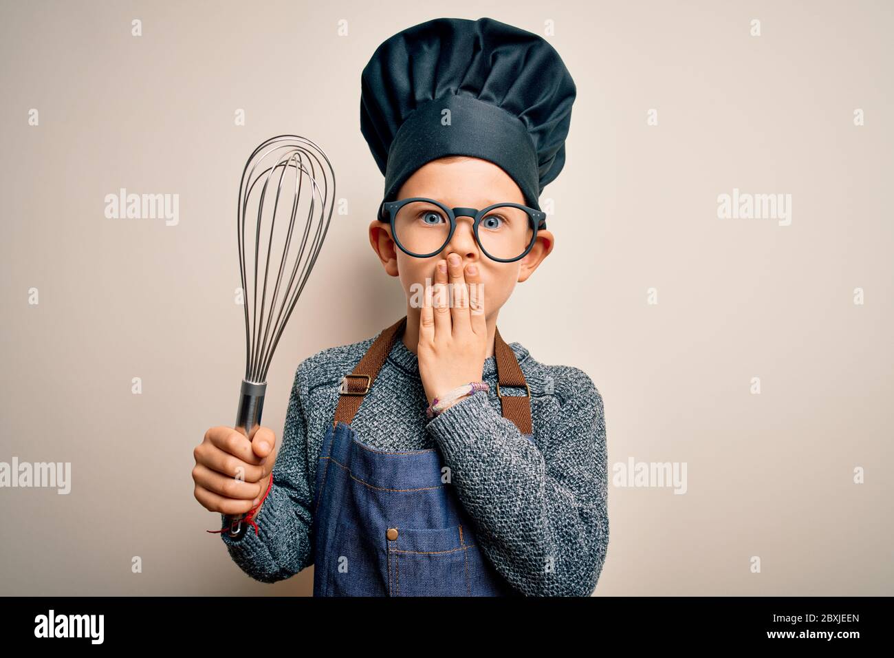 Young little caucasian cook kid wearing chef uniform and hat using