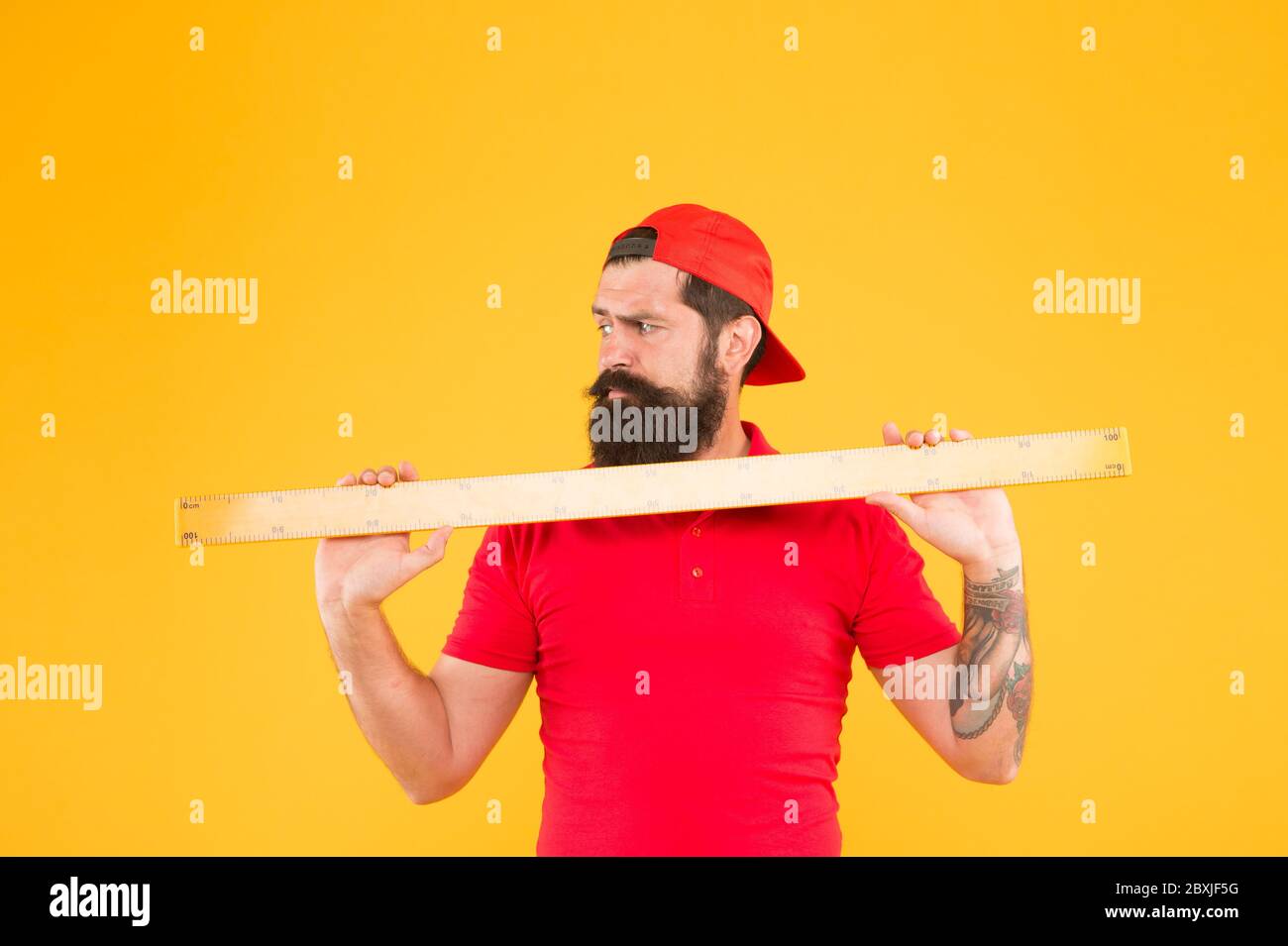 Measuring with ruler. School teacher hold ruler yellow background