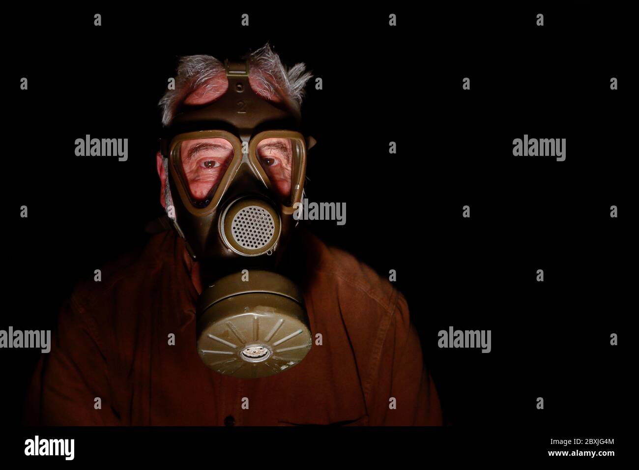 Uncertain times. Fearing the coronavirus, an older man has put on his old gas mask to protect himself. Stock Photo