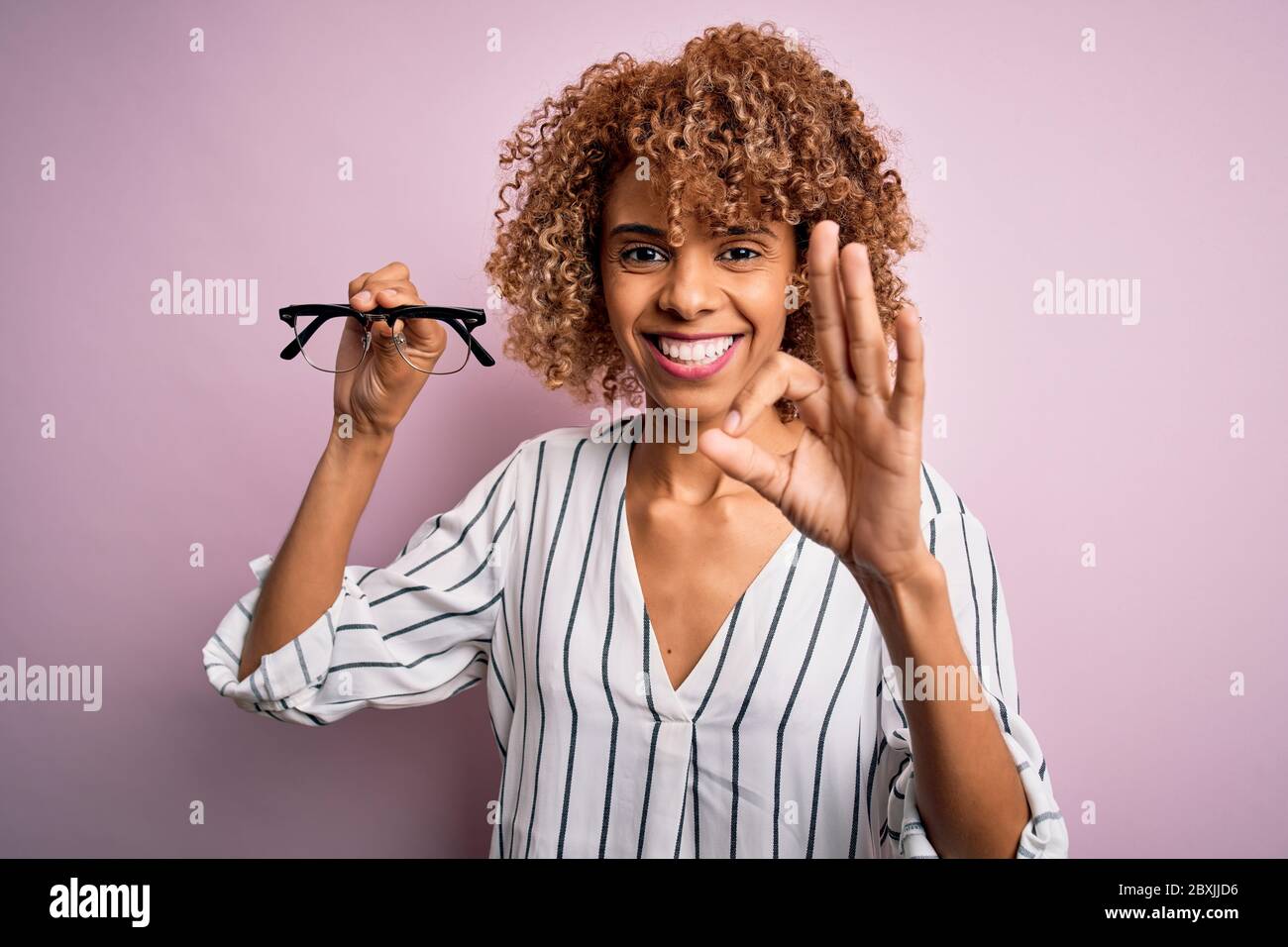 African american optical woman with curly hair holding glasses over ...