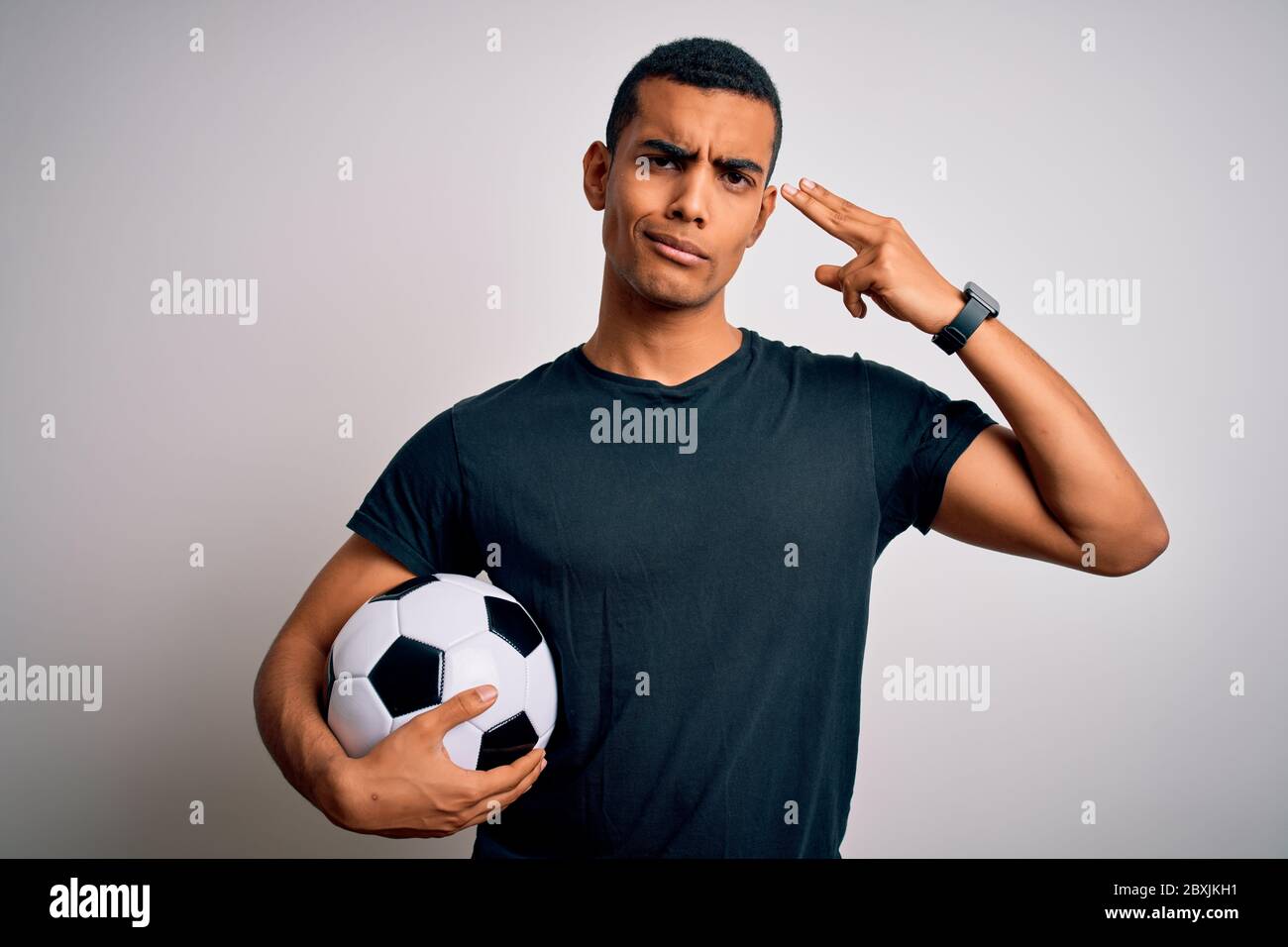 Handsome african american man playing footbal holding soccer ball over white background Shooting and killing oneself pointing hand and fingers to head Stock Photo