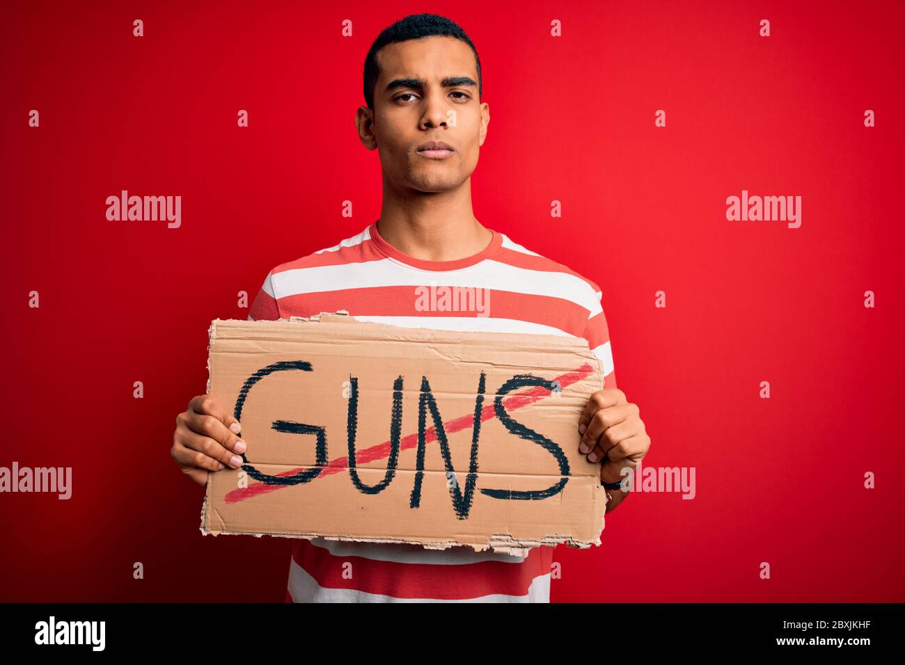 Young handsome african american man holding banner with prohibited guns ...