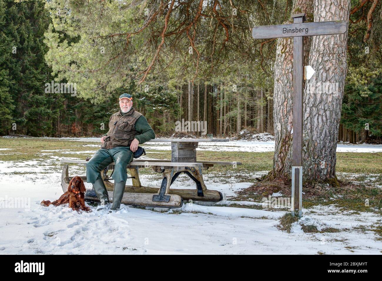 A hiker and his dog take a break at the Binsberg resting place, a popular excursion and hiking destination on the Swabian Alb in Germany. Stock Photo