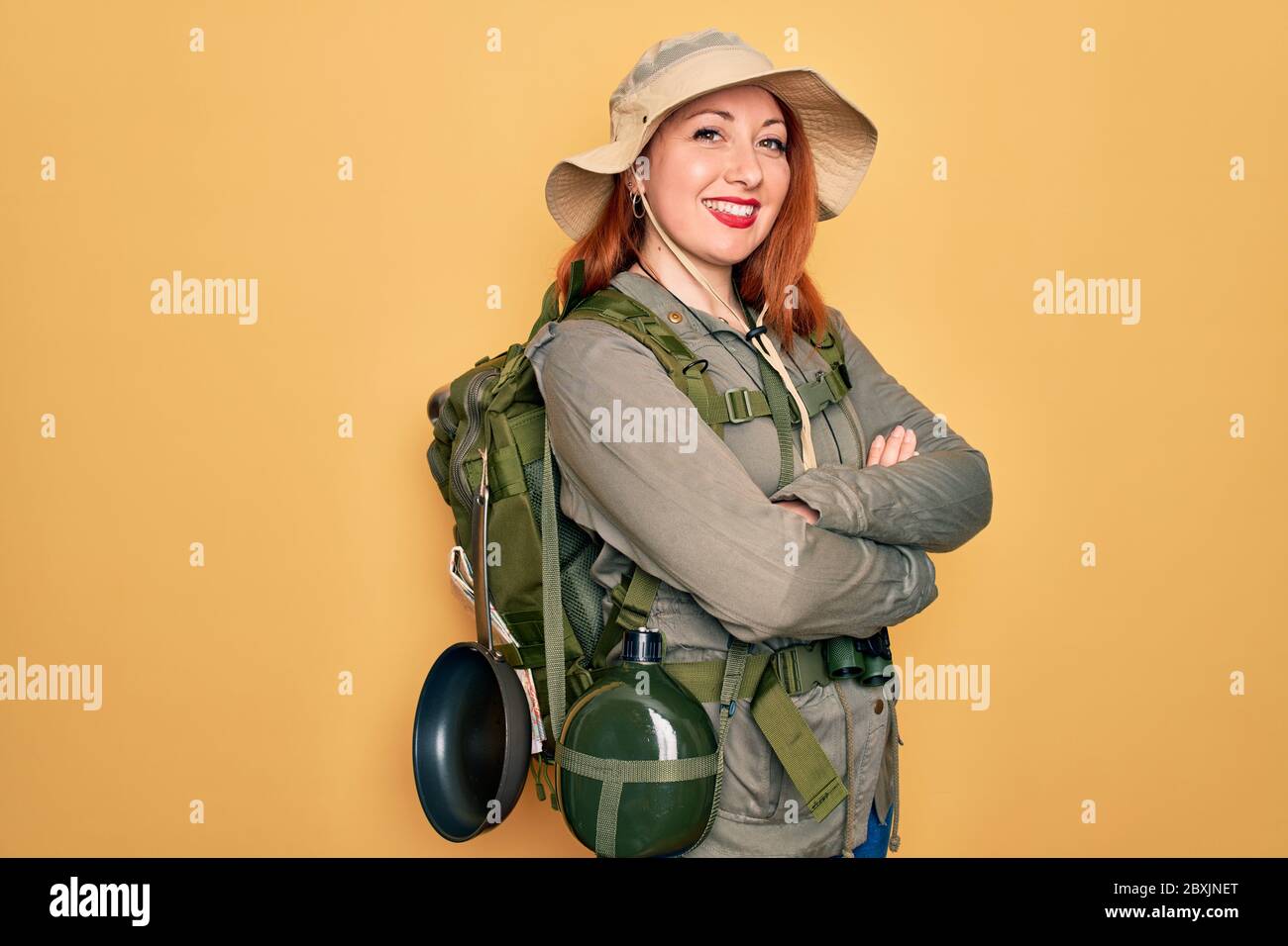 Young redhead backpacker woman hiking wearing backpack and hat over ...