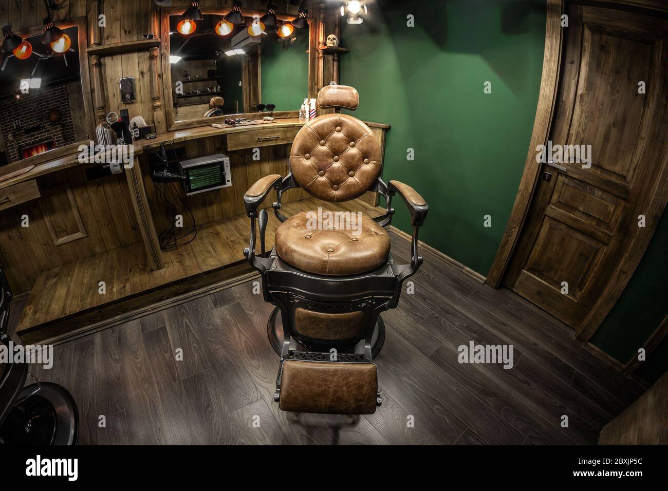 Vintage barbershop chair in the spotlight. Brown authentic interior with wood elements, tasteful design Stock Photo