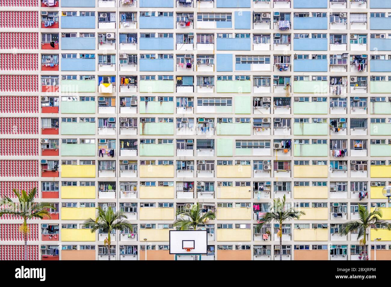 Abstract View of Dense Rainbow Coloured Housing with Palm Trees on Summers Day in Hong Kong Stock Photo