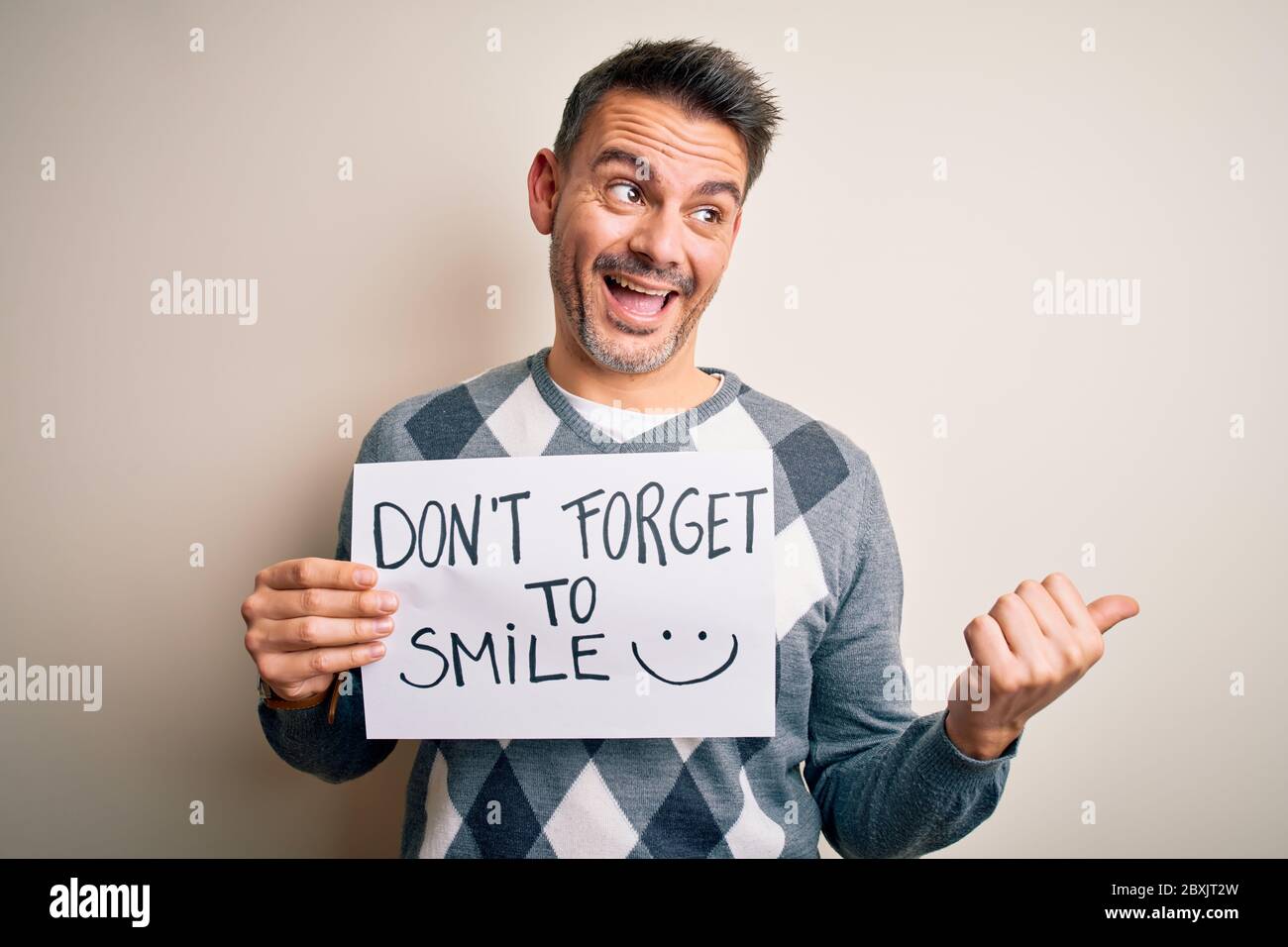Young handsome man holding banner with funny positive message over ...
