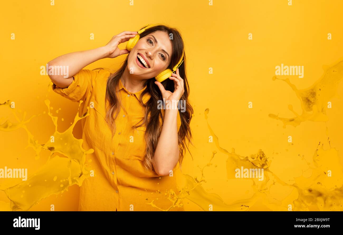 Girl with yellow headset listens to music and dances. emotional and energetic expression Stock Photo