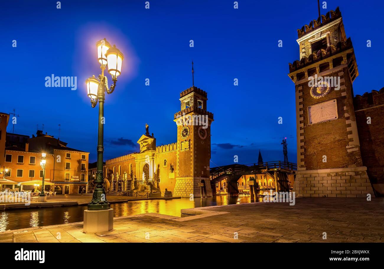 Venetian Arsenal Complex at Dusk under Blue Hour Sky and Vibrant Street Lights in Venice, Italy Stock Photo