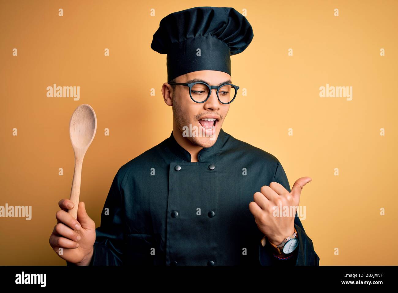 Young brazilian chef man wearing cooker uniform and hat holding wooden ...