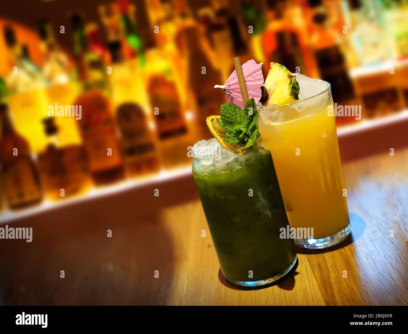 Colourful Tropical Cocktails with Umbrella at Bar with Spirits in background, London, UK Stock Photo
