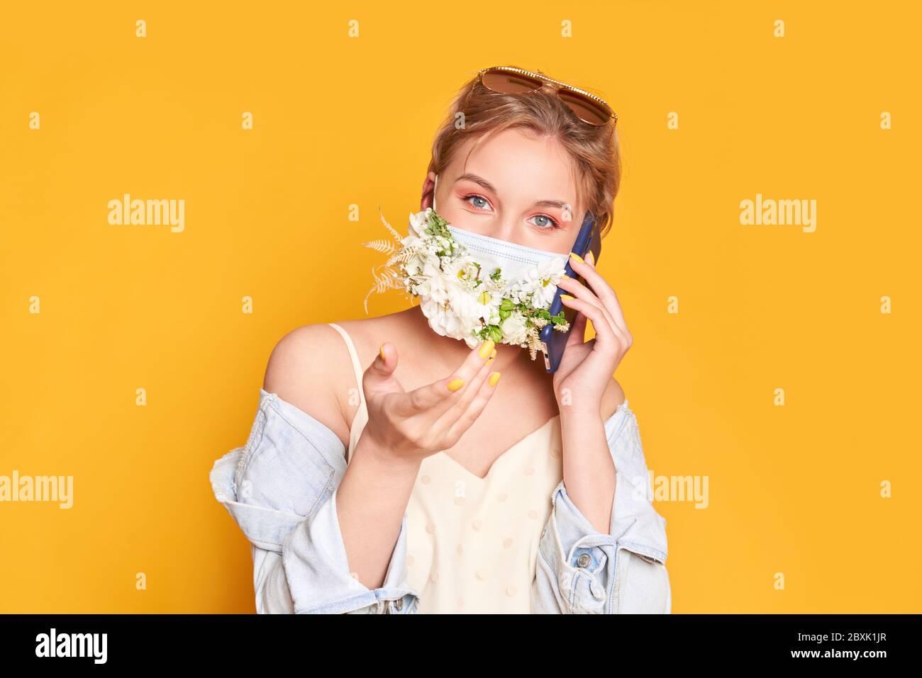 Beautiful woman in medical mask with flower design, holding telephone Stock Photo