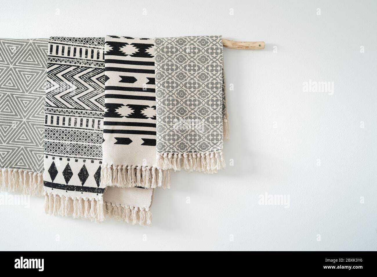 Stylish artistic carpets hanging on a wooden stick. Decoration on the